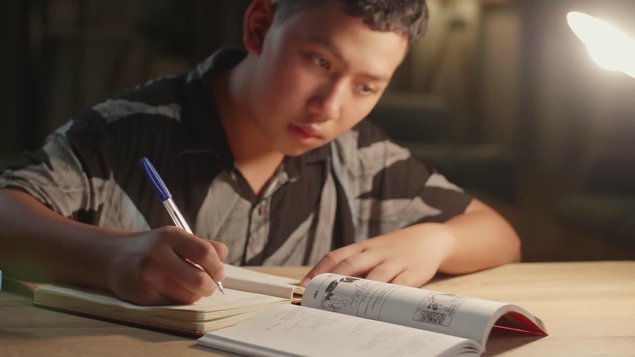 Teenage Boy Doing Homework At Table In Evening