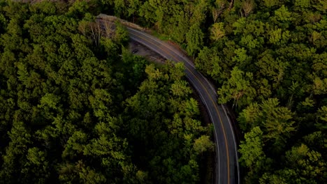 aerial drone footage of winding scenic road in appalachian mountains during beautiful summer sunset with golden light. this is in the shawangunk mountain sub-range, located in new york's hudson valley