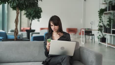 young,-beautiful-woman-in-a-suit-receives-a-joyful-message-on-her-smartphone-and-starts-laughing-and-feeling-happy