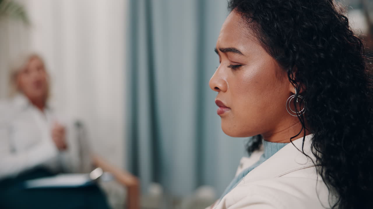 A woman listens intently to her therapist during a therapy session.