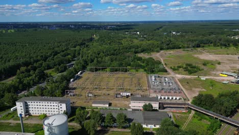hennigsdorf substation, distributing electricity and surrounded by a lush green forest in brandenburg, germany. nice aerial view flight fly push forward drone