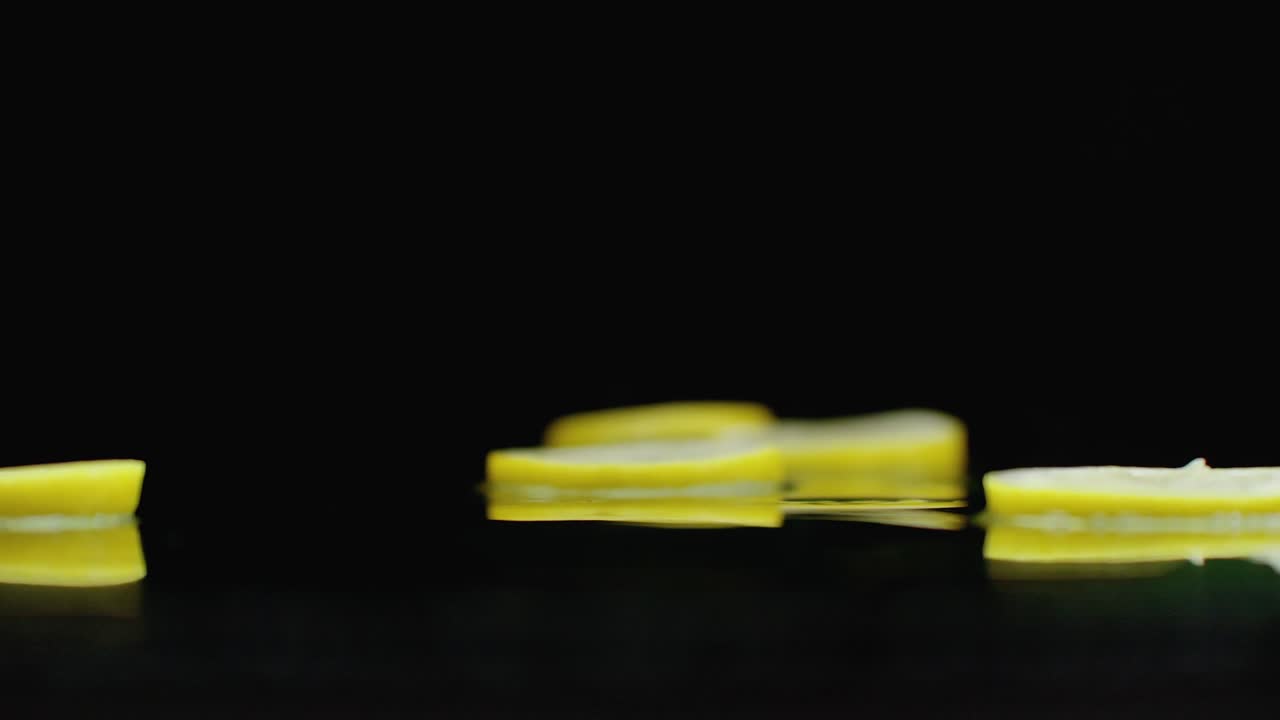 매운 프레트 조각은 반사와 스프레이와 함께 테이블에 떨어집니다. 노란색 익은 레몬의 반지의 느린 움직임