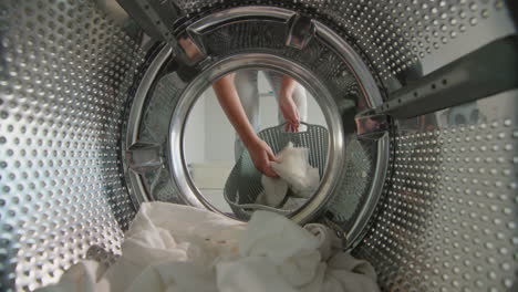 a woman puts white laundry in the washing machine