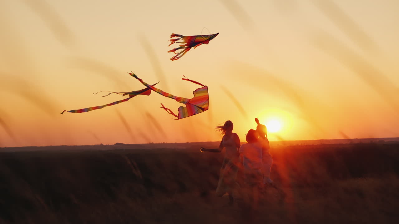 una mujer activa y sana de mediana edad juega con dos niños cometas al atardecer concepto de vacaciones de verano