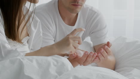 pareja aplicando desinfectante de manos en la cama