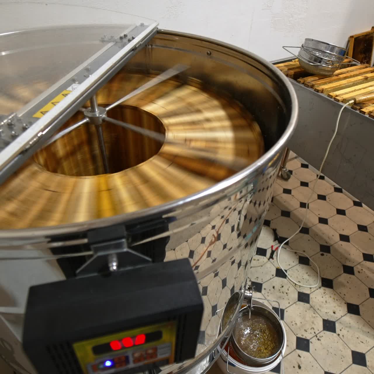Automatic electric appliance for honey extraction working at the apiary. Big metal box full of frames standing beside
