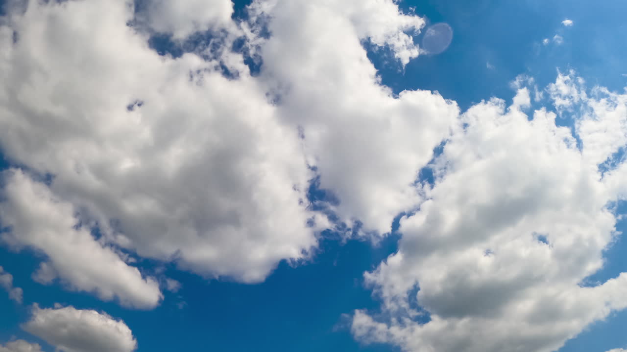 Lovely azure summer sky with fluffy white clouds. Beautiful clouds flying by the horizon from low perspective. Timelapse.