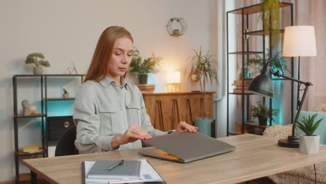 feliz mujer de negocios caucásica cerrando la computadora portátil después de terminar el trabajo relajándose en el escritorio de la oficina en casa
