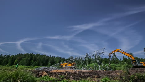 Errichten-Eines-Powerline-turmmastes-Im-Ländlichen-Europa-Mit-Kran,-Bagger-Und-Anderem-Schwerem-Gerät---Bauzeitraffer