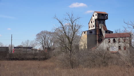 freight train passes an old abandoned rusting mill or factory suggests the end of america as an industrial power