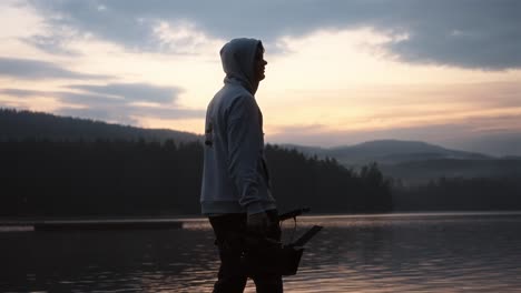 man walking with a camera by the lake in norway during a cloudy sunset