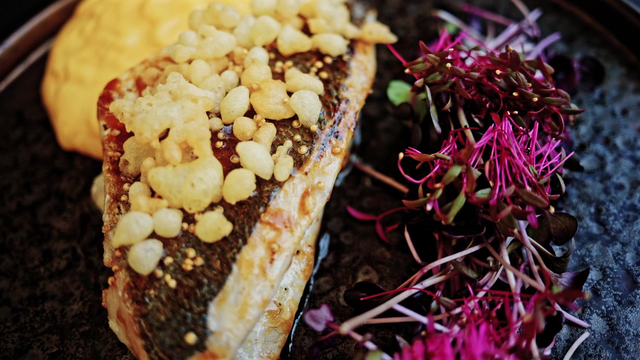 Close up of a pan seared white fish fillet with crispy skin, topped with crispy puffed grains