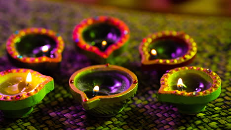 video of glowing lit diwali candles in circle on woven purple to green surface