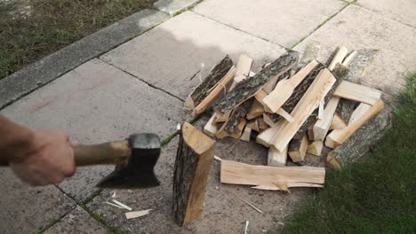 Young man is chopping wood in smaller pieces and putting it aside