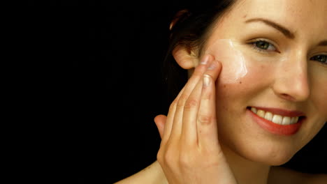mujer sonriente aplicando crema
