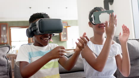 Happy-african-american-brother-and-sister-using-vr-headsets-on-sofa,-slow-motion