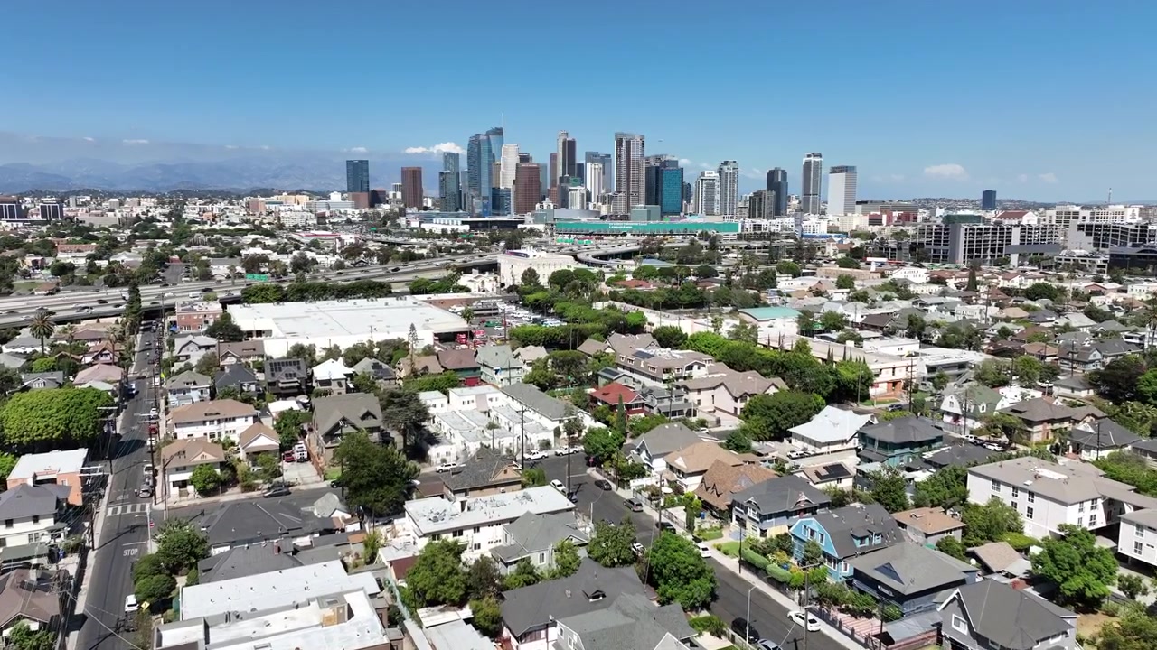 Riprese aeree che mostrano lo skyline del centro di Los Angeles in una luminosa giornata estiva di sole, con alti edifici commerciali e residenziali che circondano LA.