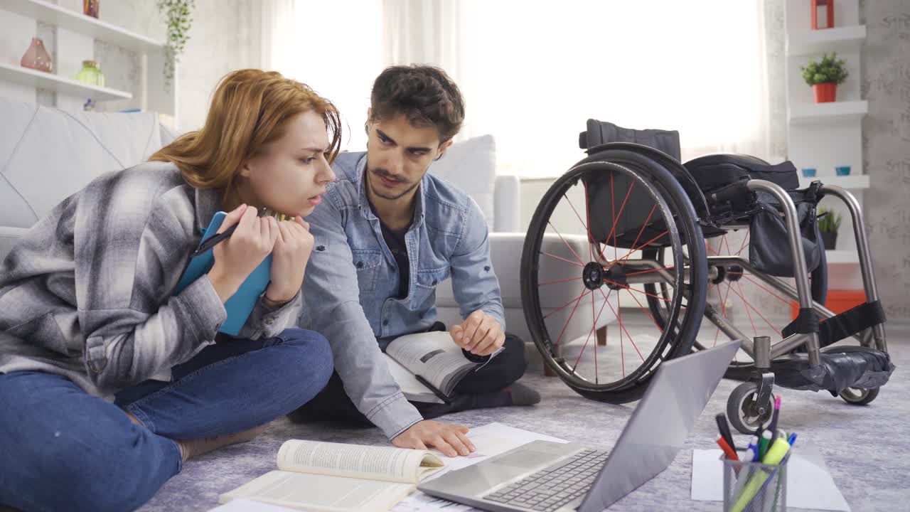 un estudiante con una discapacidad y una niña miran una computadora portátil y libros en casa.