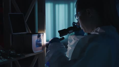 a female expert criminologist removes fingerprints from a jewelry box with a brush a woman gathers a female expert criminologist removes fingerprints from a jewelry box with a brush a woman gathers evidence using a flashlight at the crime scene in a dark apartment lit by red and blue police sirens
