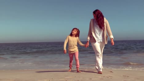 Mother-and-daughter-walking-on-sand-