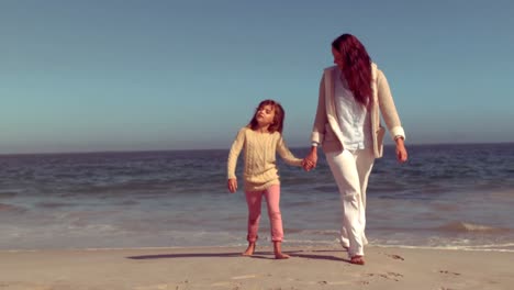 mother and daughter walking on sand