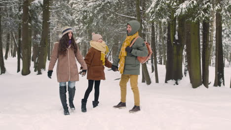 vista frontal de padres e hija vestidos con ropa de invierno en un bosque nevado