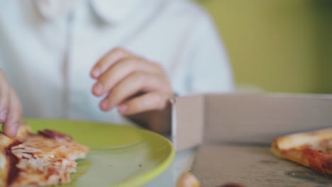 el escolar se sienta a comer una deliciosa pizza en la mesa en cámara lenta.