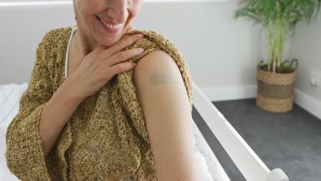 happy caucasian senior woman showing plaster after vaccination