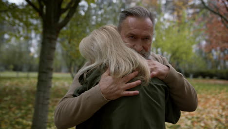 closeup view of happy lovers standing in park. senior man caressing woman.