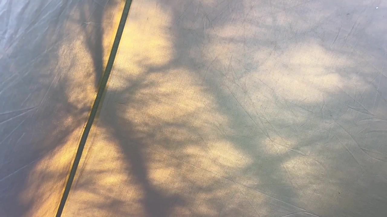 Natural light and tree shadows creating patterns on a camping tarp.