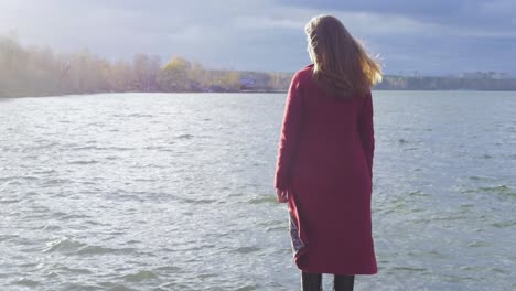 woman in red coat by the river