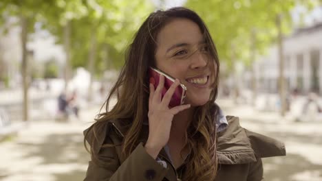 emotional young curly brunette talking to interlocutor through phone.