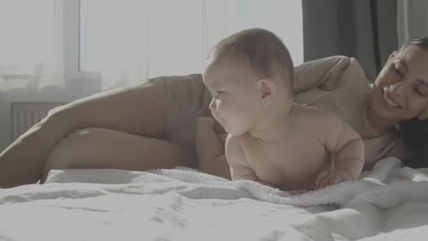 mom and cute happy baby laying in bed