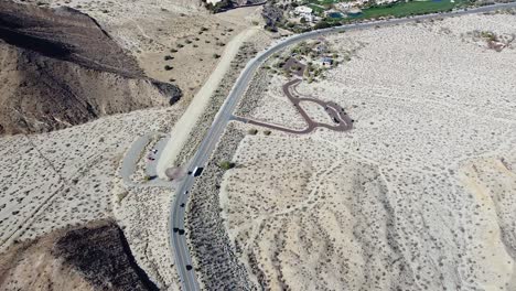 carretera del desierto que conduce a un pequeño pueblo con hierba verde, disparo de drones a gran altura