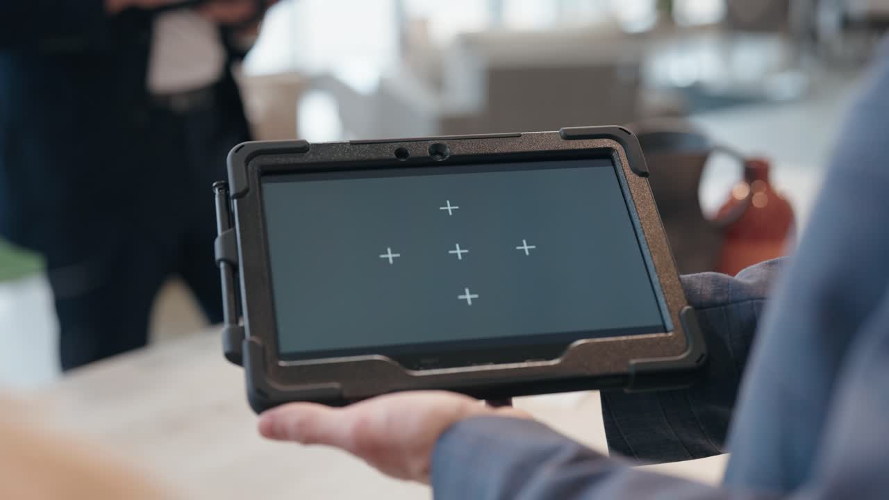 Camera glides forward between people as suited presenter shows tracked tablet