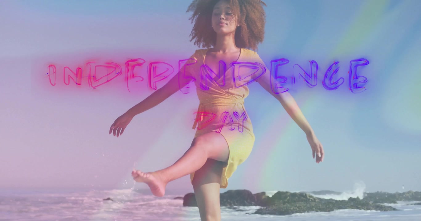 Ballerina che solleva il piede dalla sabbia, accendendo un testo al neon "Independence Day" per uno spot pubblicitario che si immerge tra le onde.