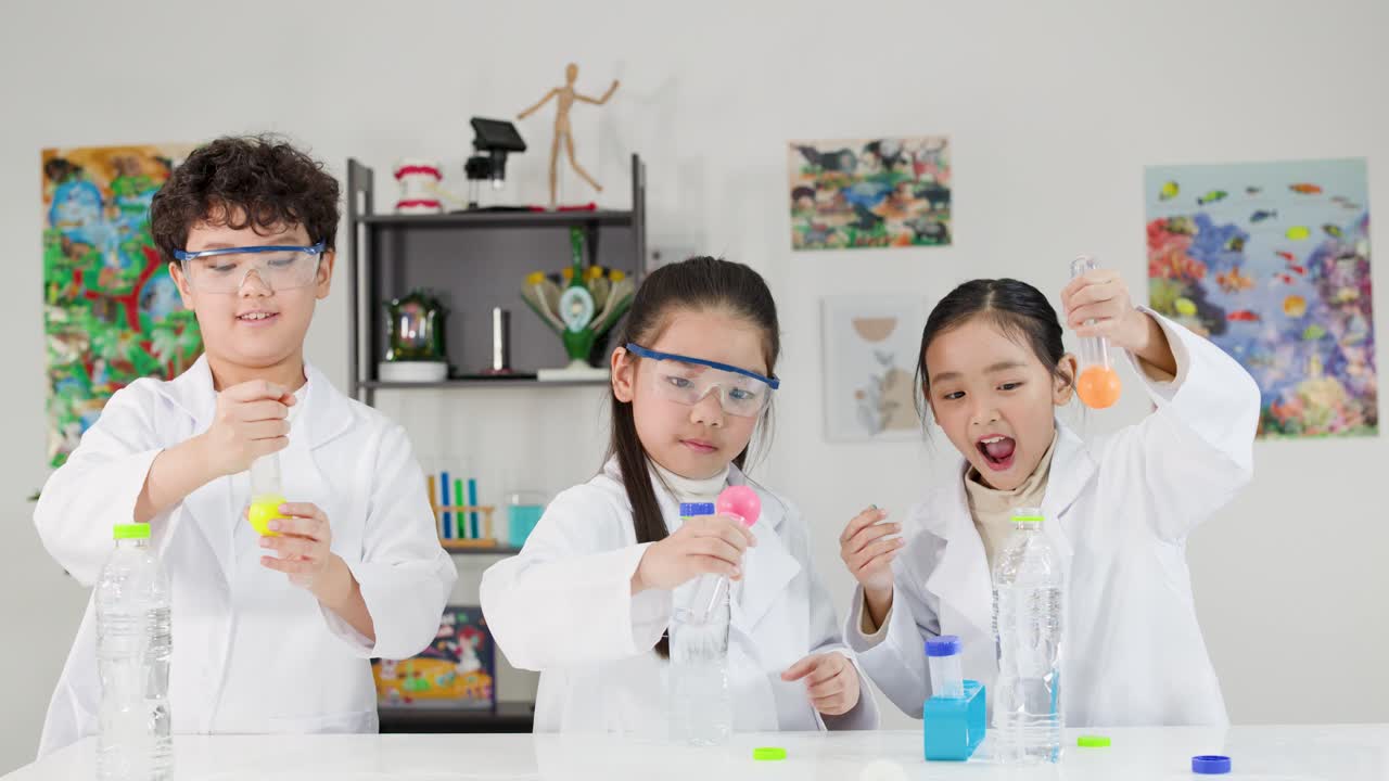白衣を着た3人の若い生徒が、瓶とボールを使って物理実験を行っている。
