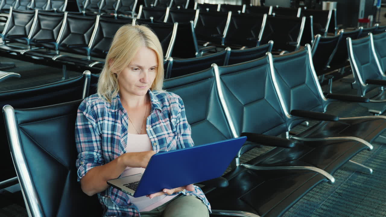 женщина пользуется ноутбуком в зале ожидания аэропорта в ожидании рейса