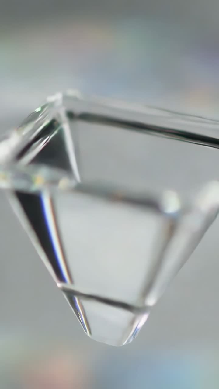 Vertical video: Camera shifting, revealing clear inverted prism in studio to expose tip and glints