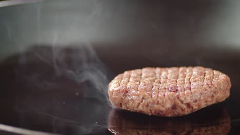 on a hot frying pan the man puts the burger meat.