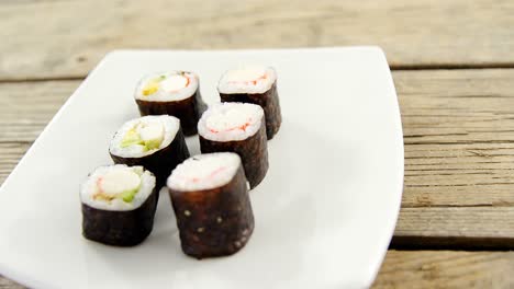 maki sushi served on plate against wooden background