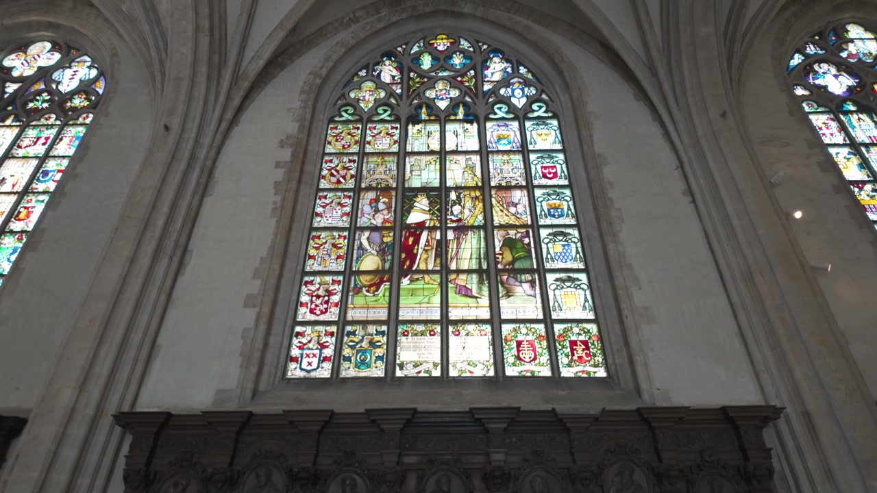Vista interna della Cattedrale di Nostra Signora di Anversa, luce che filtra attraverso vetrate colorate su statue lignee di discepoli