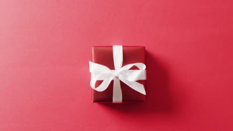 Video-of-red-christmas-gift-and-copy-space-on-red-background