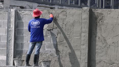 worker applying plaster to a concrete wall.