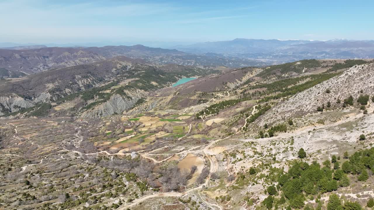 toma aérea de un hermoso paisaje rural con sinuosos caminos de tierra y un pequeño pueblo en la distancia