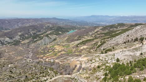 Toma-Aérea-De-Un-Hermoso-Paisaje-Rural-Con-Sinuosos-Caminos-De-Tierra-Y-Un-Pequeño-Pueblo-En-La-Distancia