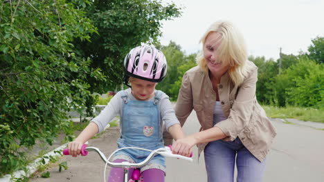 mom teaches daughter to ride a bicycle
