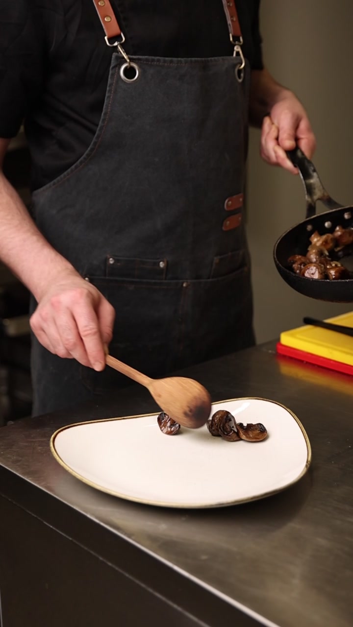 Chef che impiattano con cura funghi trifolati in una cucina professionale