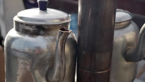 close up of two metal kettles boiling water on a stove