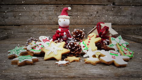 video composition with falling snow over desk with ginger cookies and santa doll